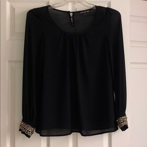 A black sheer shirt with gold charms